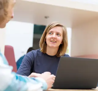Vrouwelijke student aan tafel atrium met laptop